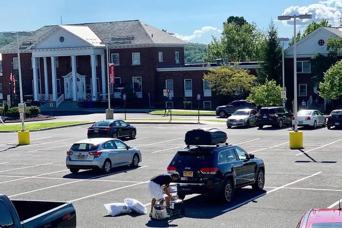 A student in a parking lot at SUNY Oneonta unloading a car of items for the dorm